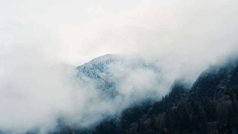 Mountains are enshrouded by dense fog.