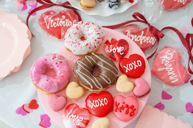 A valentine's day table with a heart shaped plate of donuts