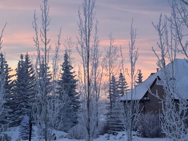 A cabin in a snowy picture at sunset