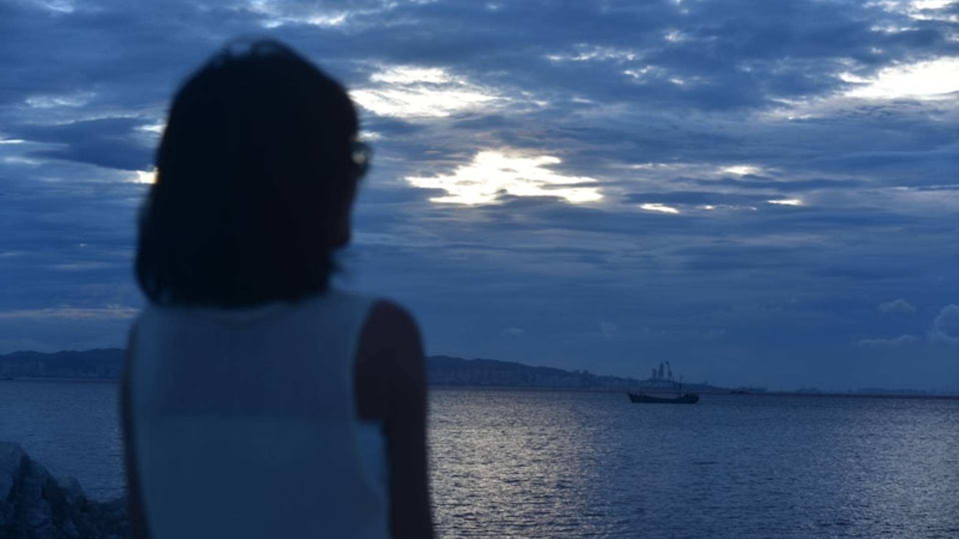 a woman looking at a boat in the ocean