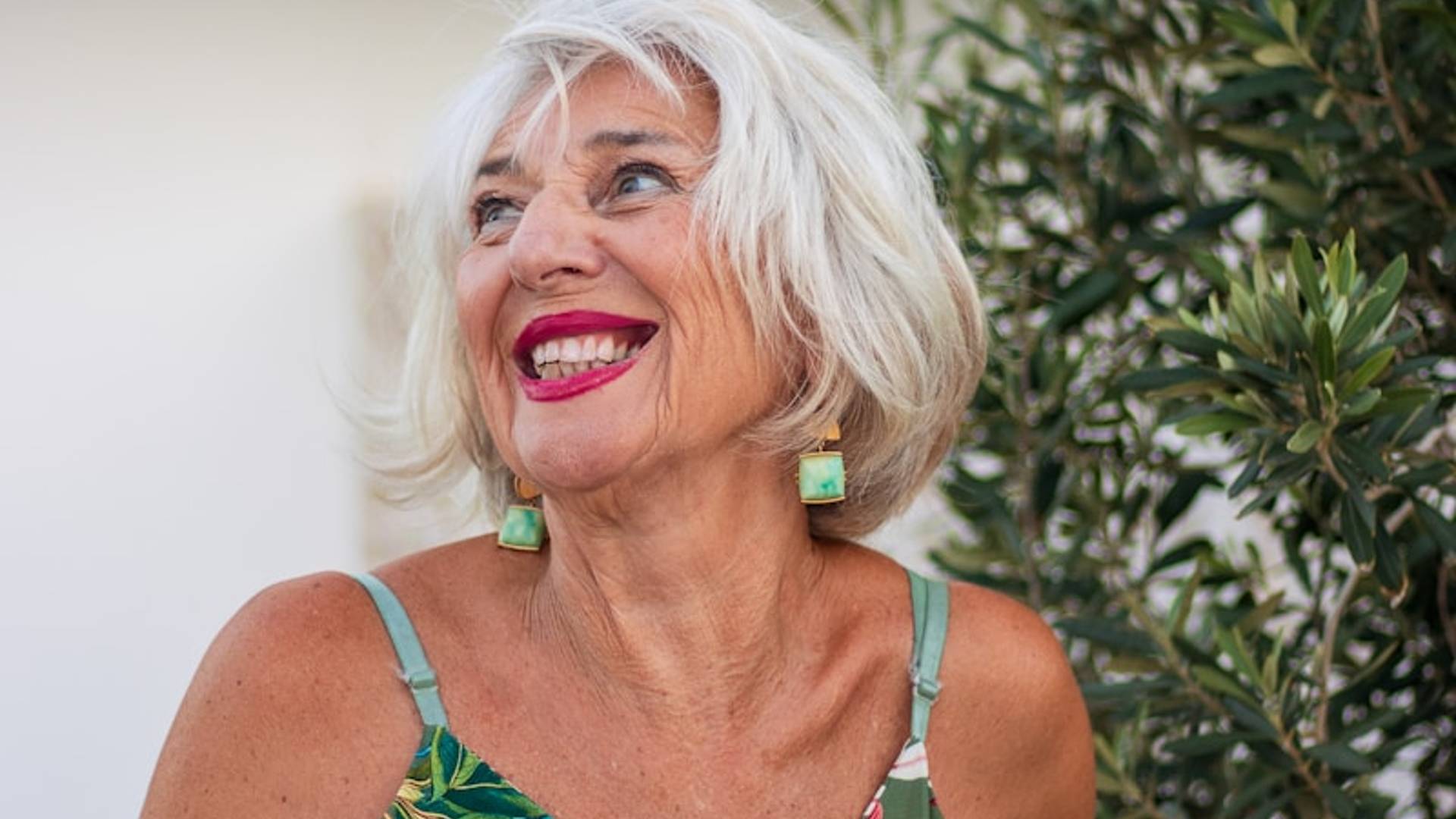 Smiling older woman with grey hair and floral dress.