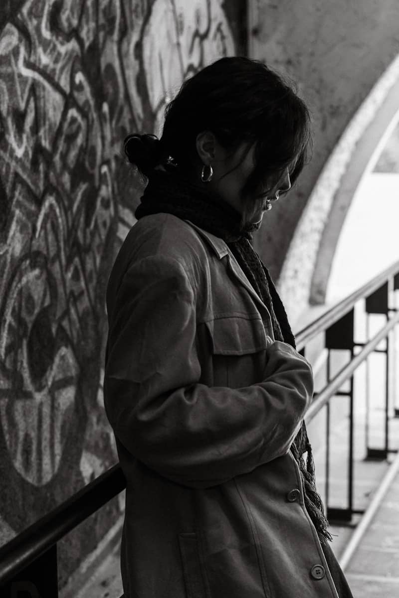 Woman in coat stands near graffiti wall