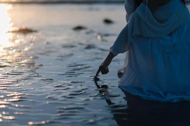 A person touches the water near the shore.