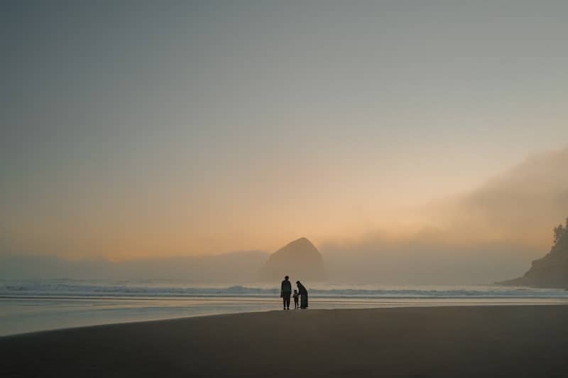 Family walking on a foggy beach at sunset