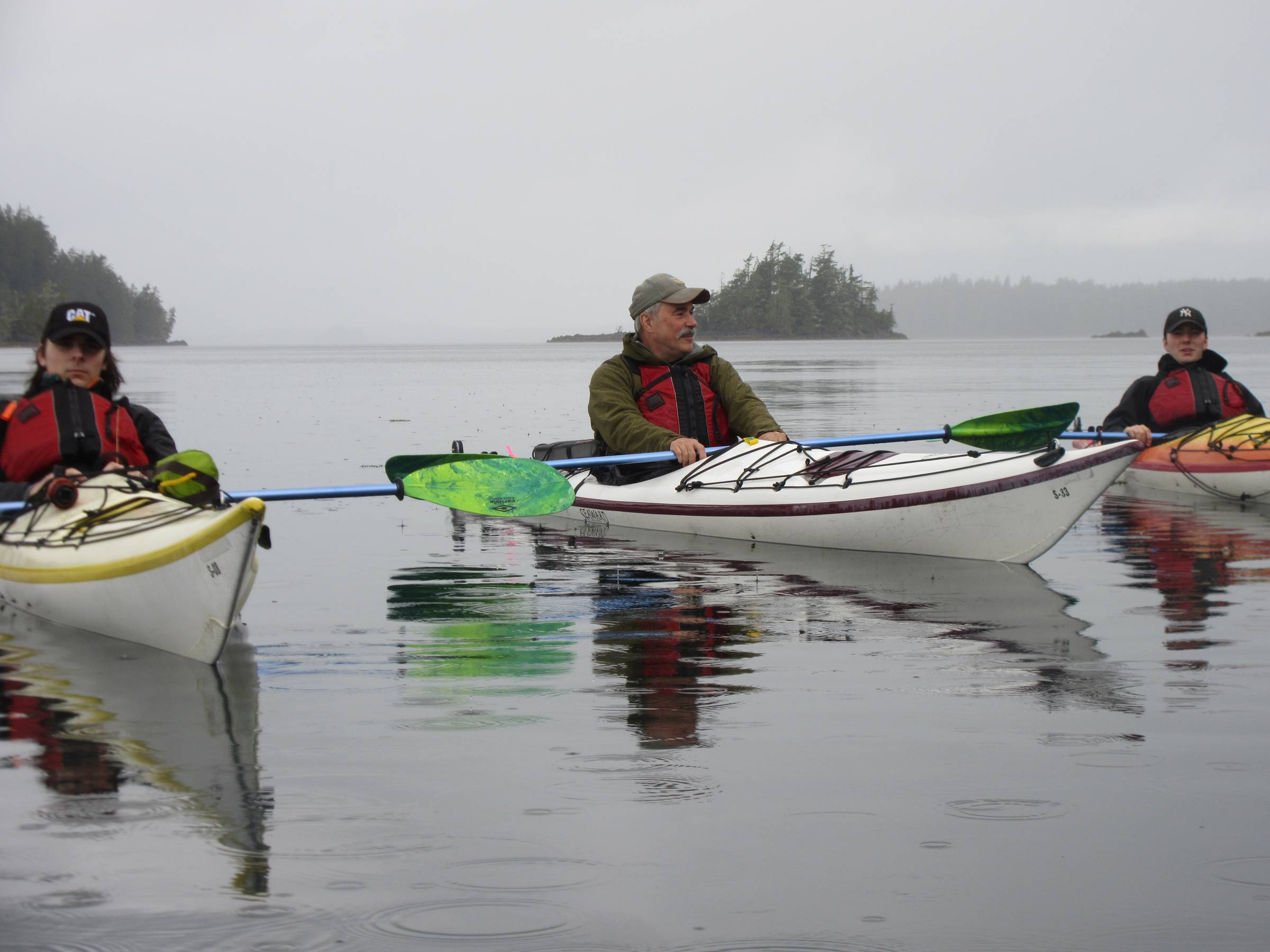3 males sitting in kayaks on ocean