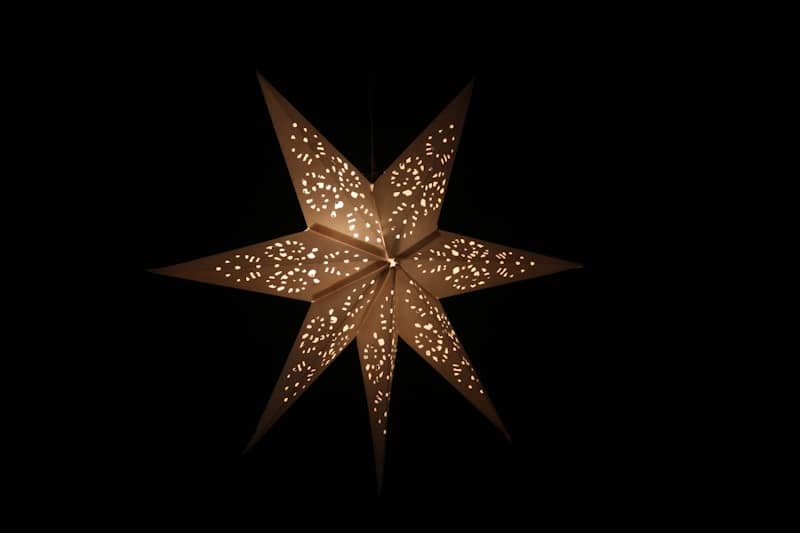 A lit paper star lantern hangs against a black background.