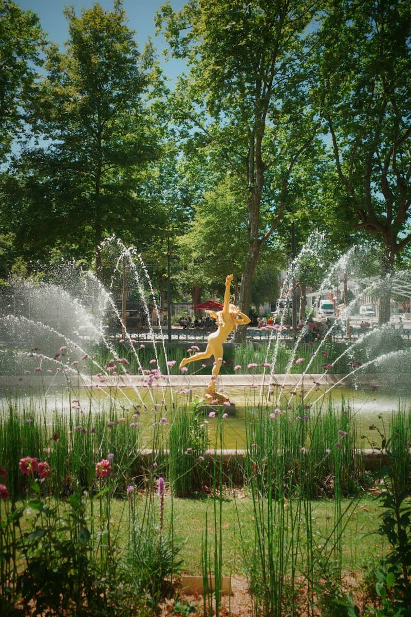 Fountain with statue surrounded by water and greenery.