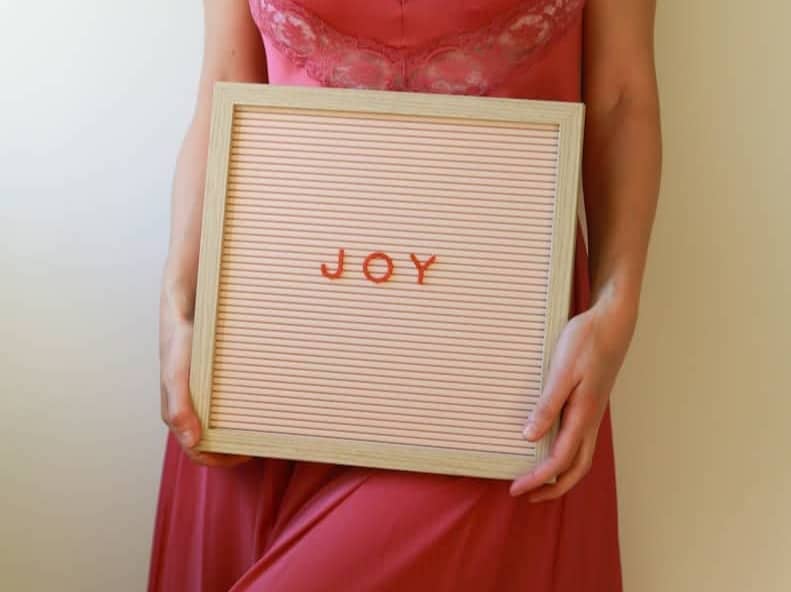 Woman holds a sign that says "joy."
