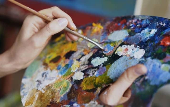 Artist mixing paints on a colorful palette with brush