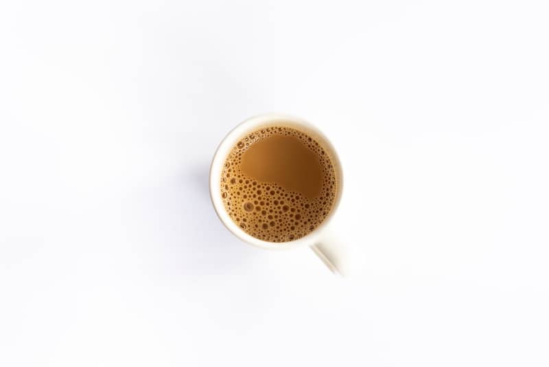 A white mug filled with coffee on a white background