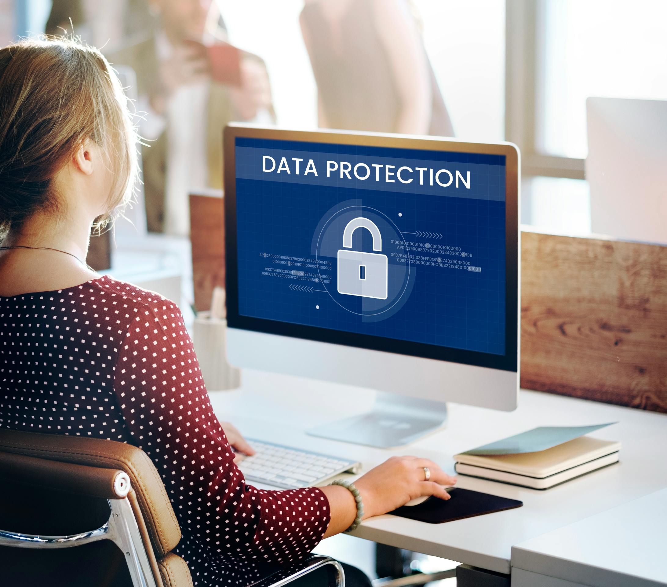 Women looking at a computer screen with "Data Protection" and a picture of a lock on the screen.