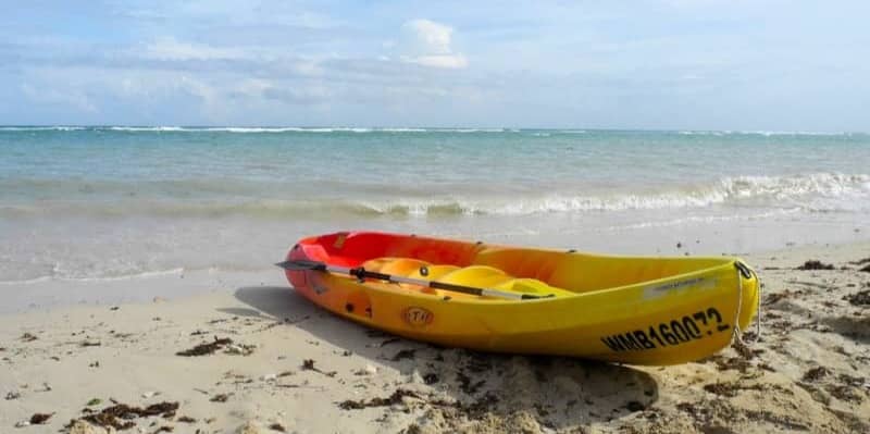 A yellow and red kayak rests on a sandy beach.