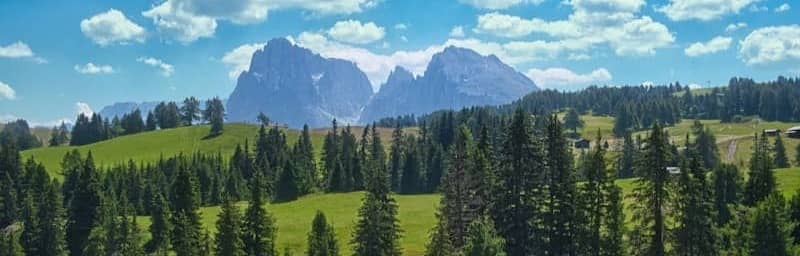 Mountains and trees under a beautiful, cloudy sky.