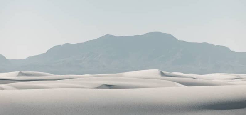 White sand dunes with a distant mountain range.