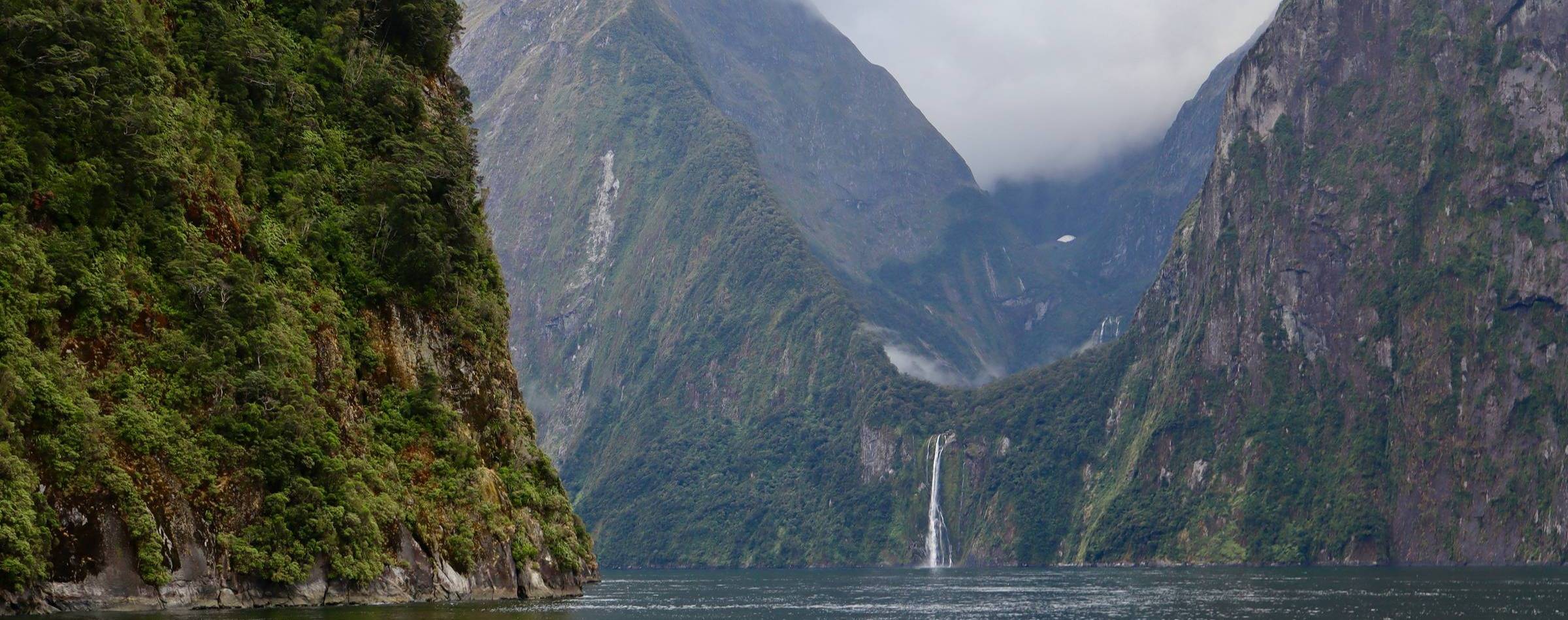 waterfall over lush green mountains into a fiord