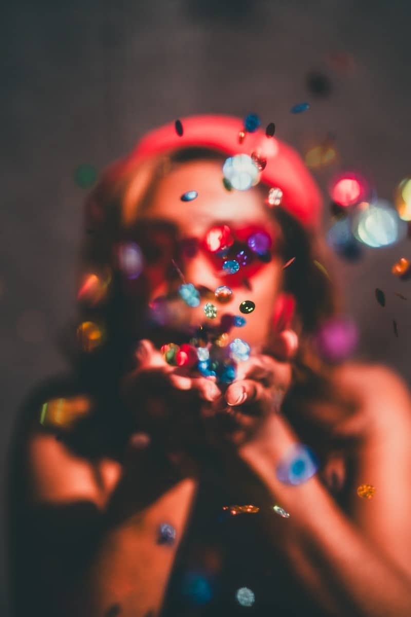 A woman is blowing confetti on her face