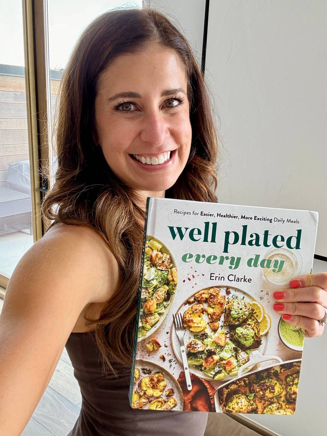 Erin Clarke holding Well Plated Every Day cookbook