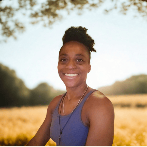 woman in black pants and pink shirt standing on green grass field during daytime