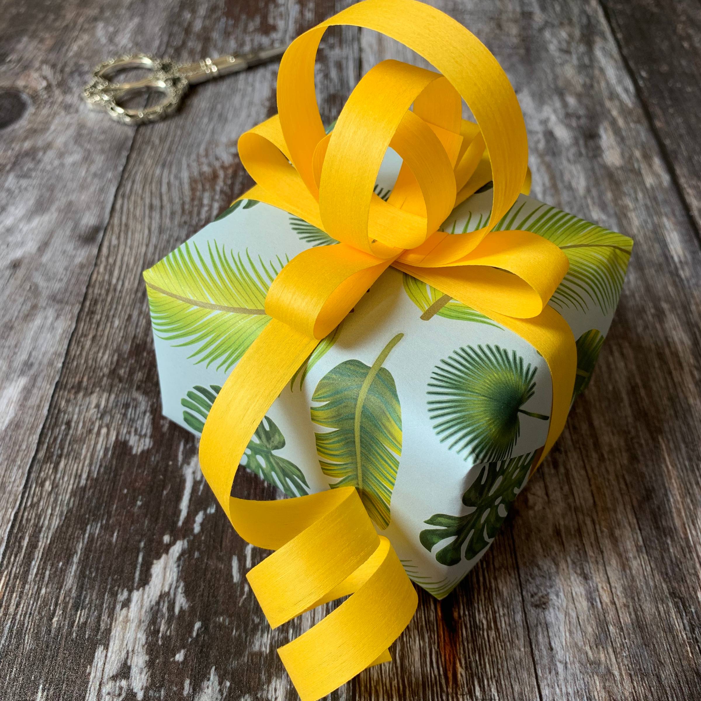 Green & Blue Tropical wrapping paper with a yellow curled and looped bow 