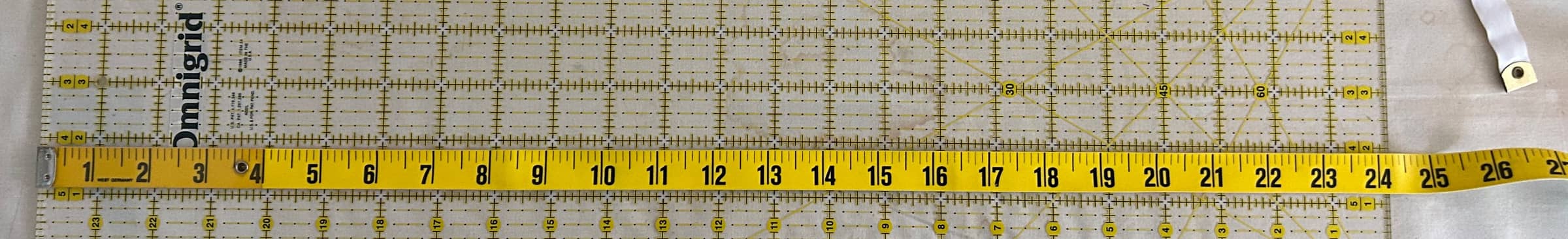 A tape measure on top of a quilting ruler.