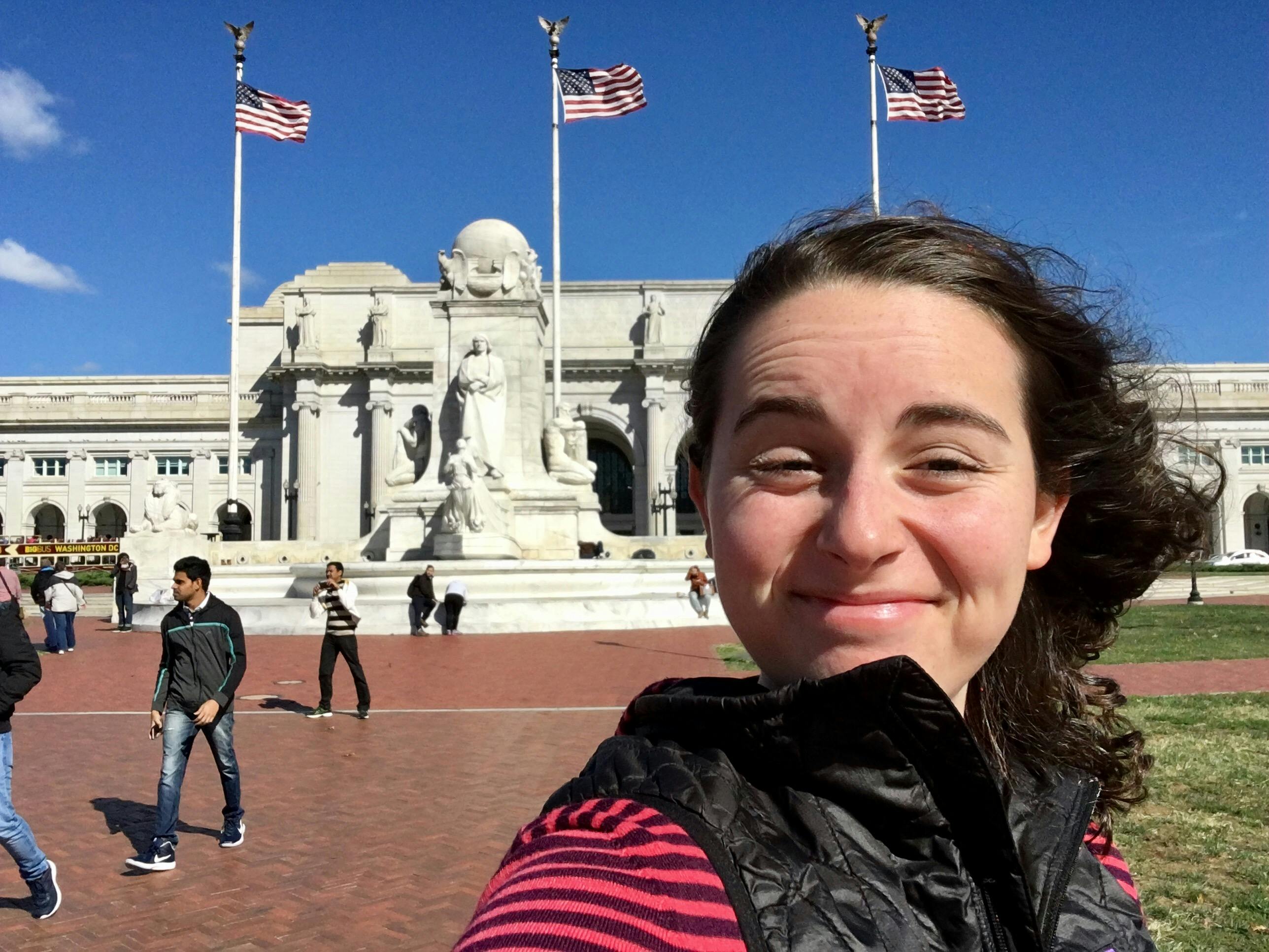 A picture of a woman smiling on a clearly windy day in front of Union Station in Washington, D.C.