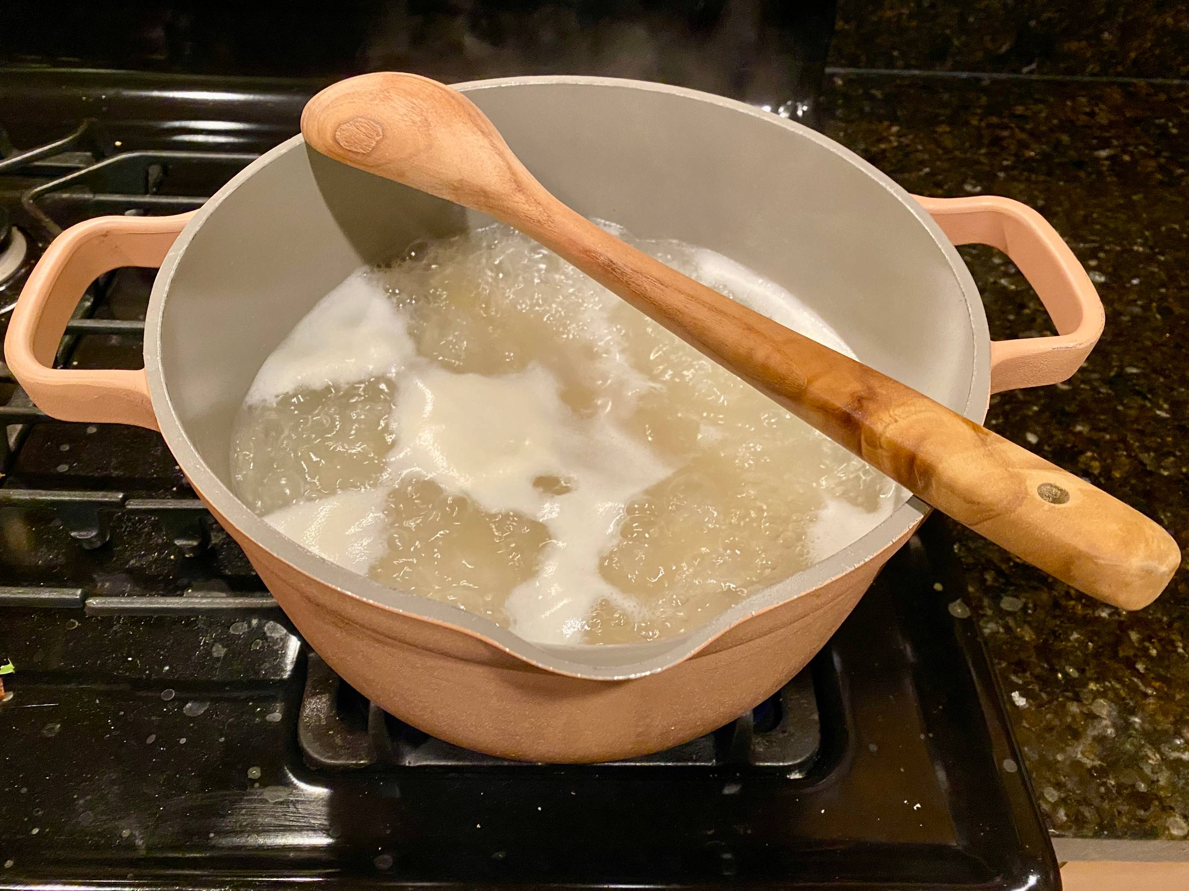 A wooden spoon over a boiling pot