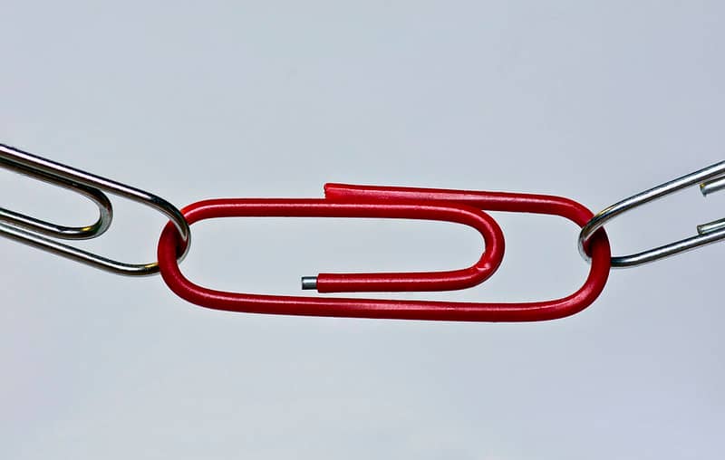 a chain of paperclips with a red one in the middle