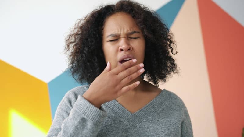 Young woman sneezing with hand over mouth.