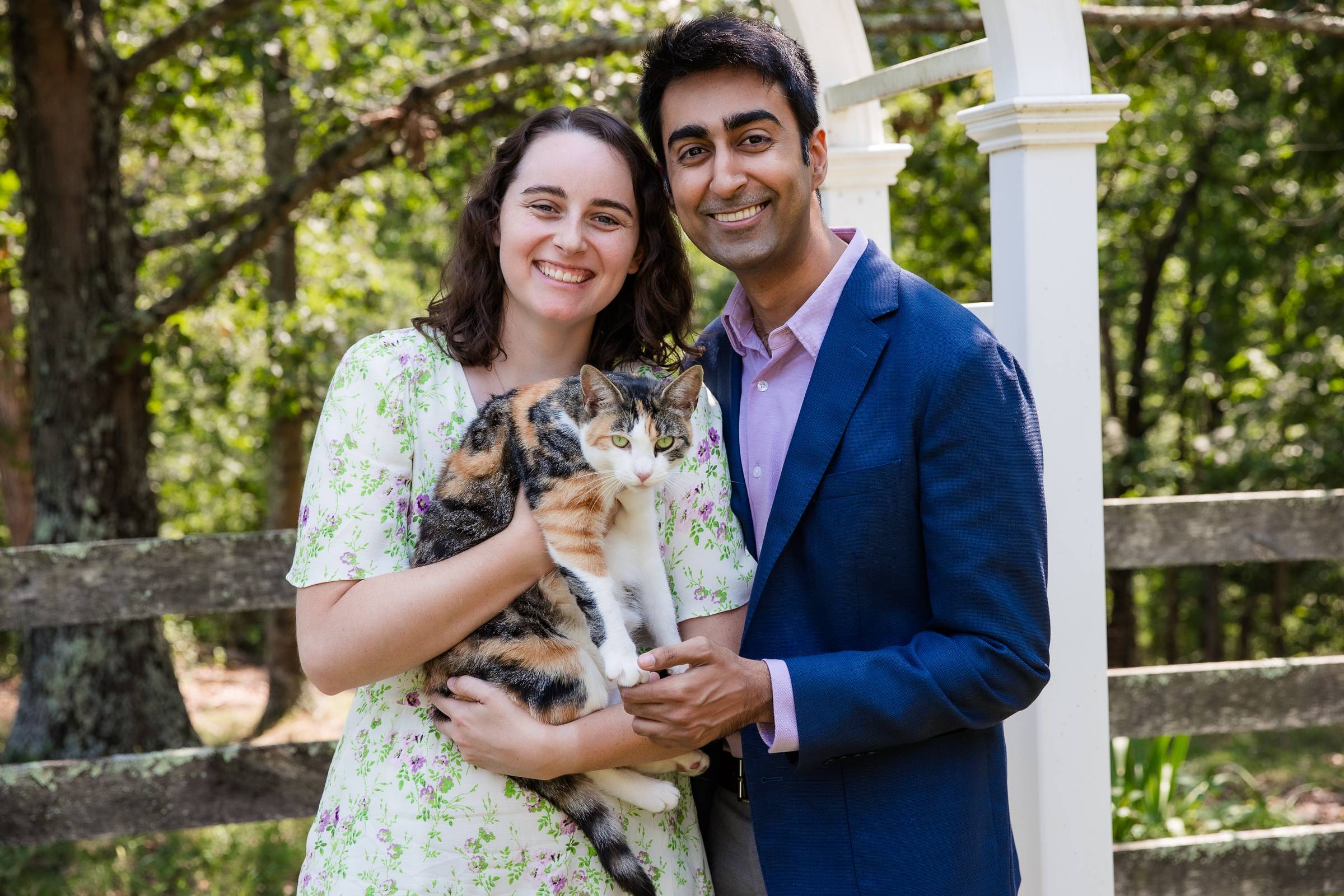 A couple happily posing with a calico cat 