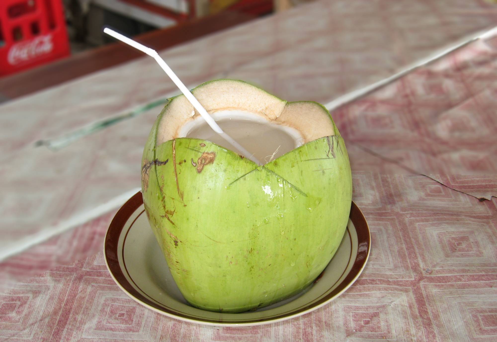A green young coconut opened with a straw inside to drink the coconut water. 