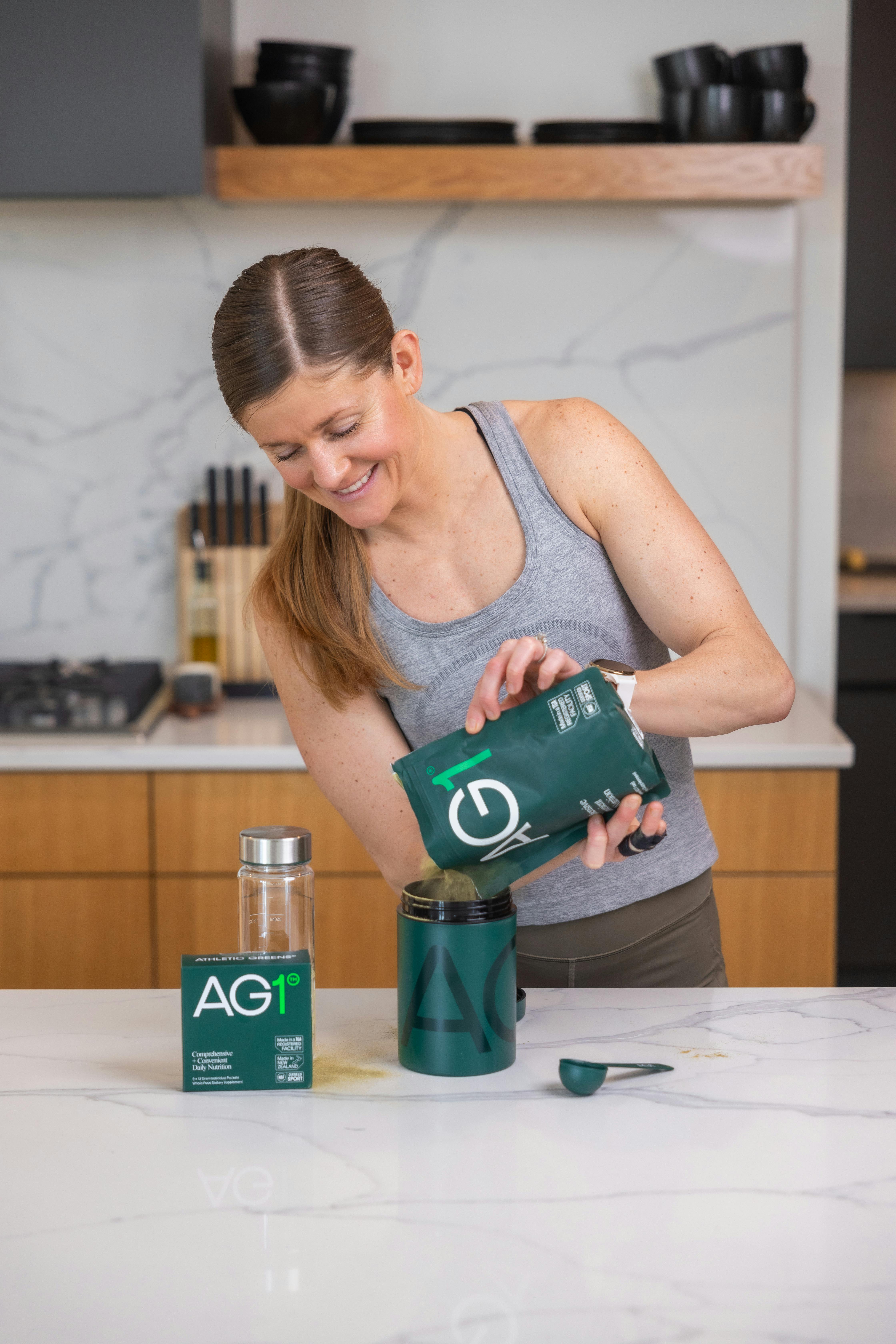 Lindsey pouring AG1 into a canister