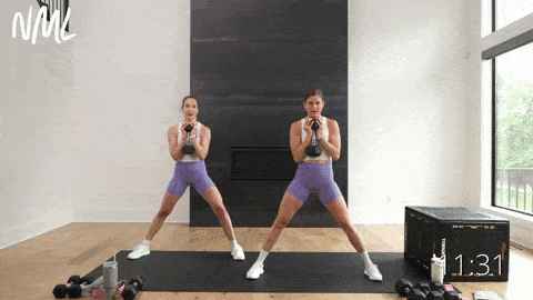two women performing a lateral squat with a dumbbell