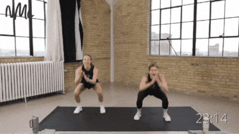 two women performing a squat pulse and squat jack