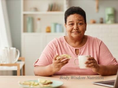 A woman eating and holding a mug