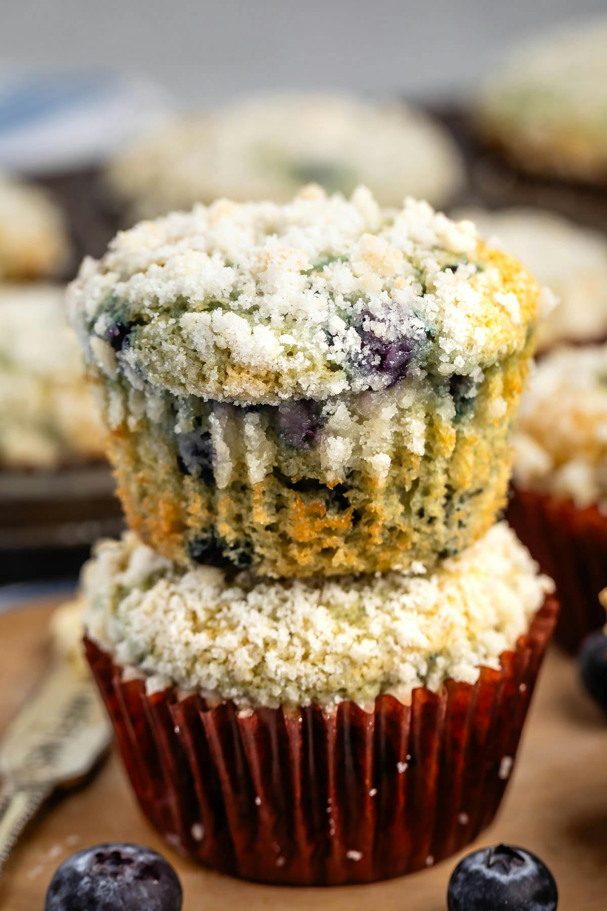 stacked blueberry muffins with a streusel crumble on top of both and blueberries baked in. 