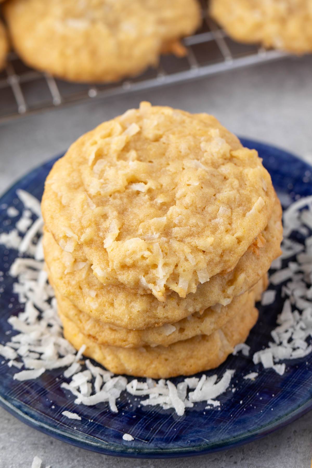 stacked cookies on a navy blue plate with coconut baked in and sprinkled around.