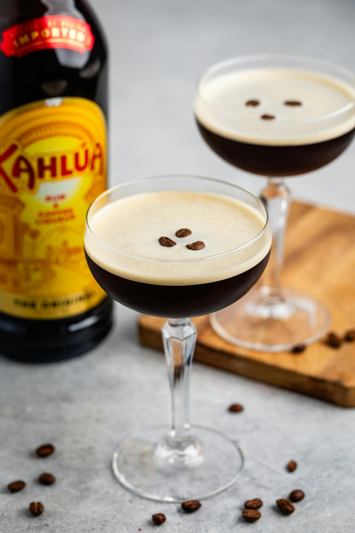 espresso martini in a tall clear martini glass with coffee beans in the center.