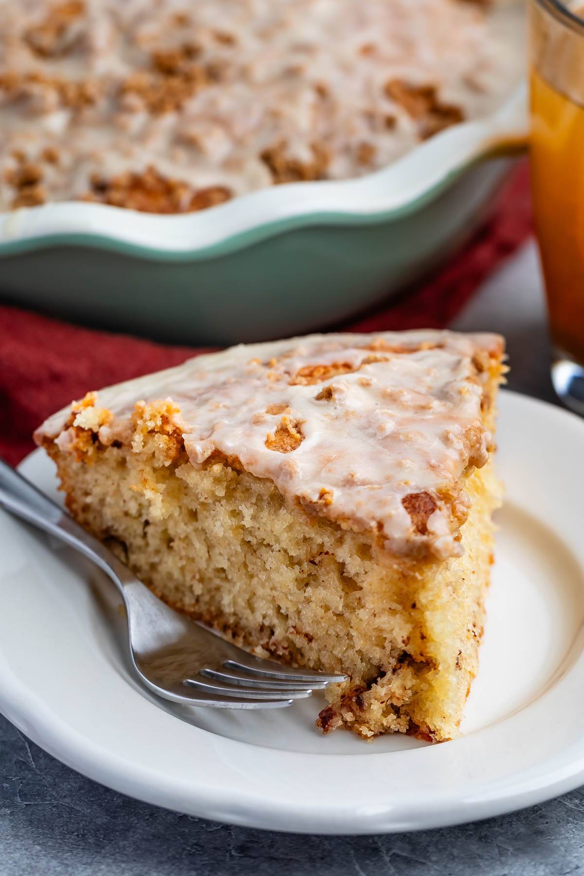 one triangle slice of coffee cake on a white plate next to a fork. 