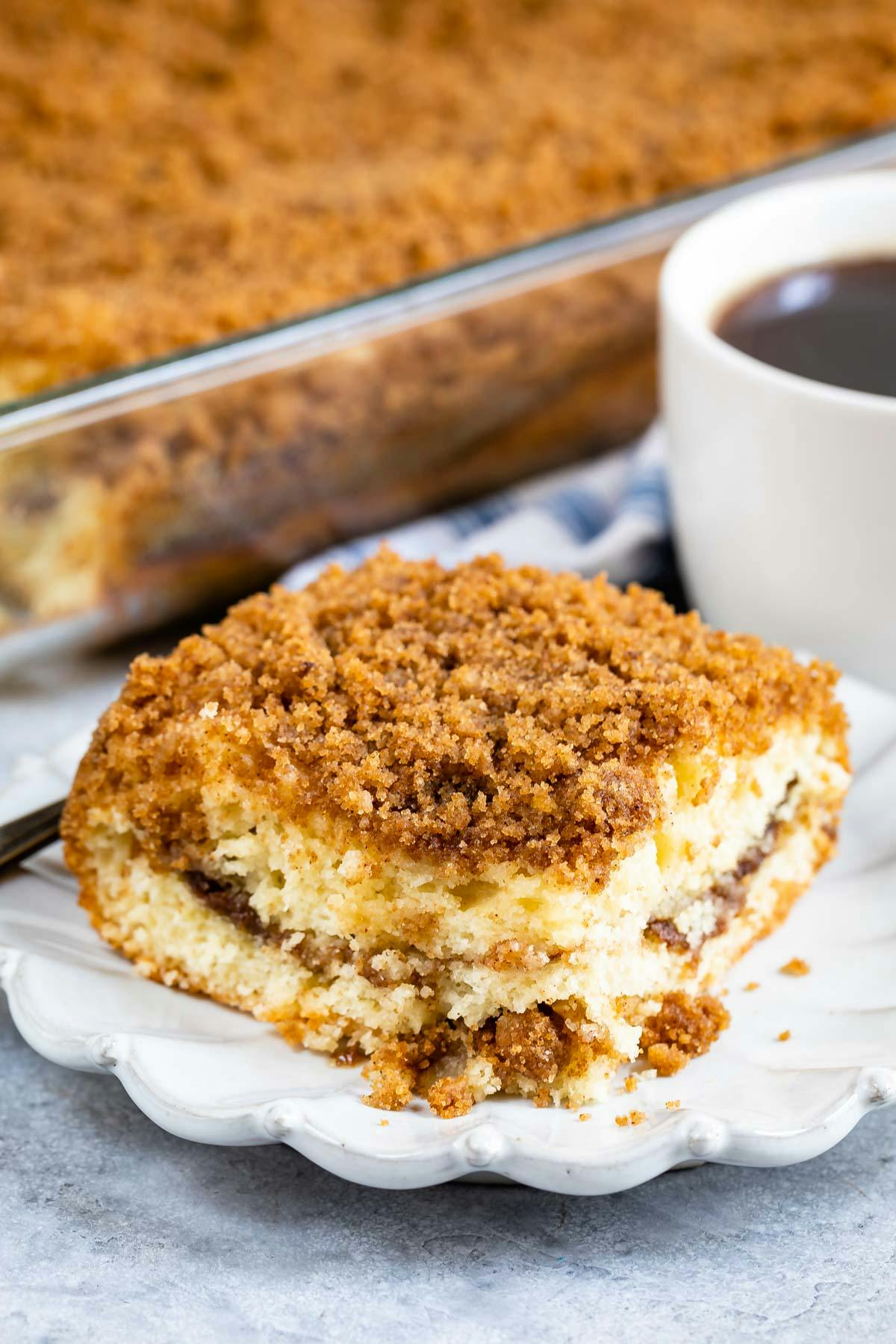 one slice of coffee cake on a grey plate with streusel crumble topping on top. 