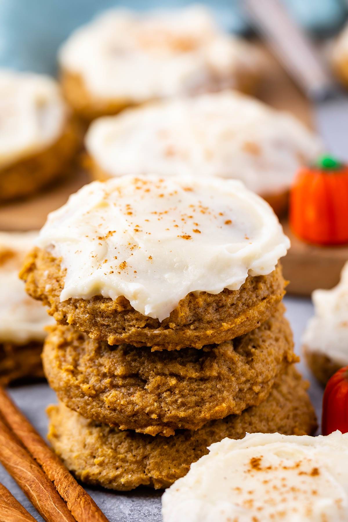 stacked pumpkin cookies with white frosting on top.