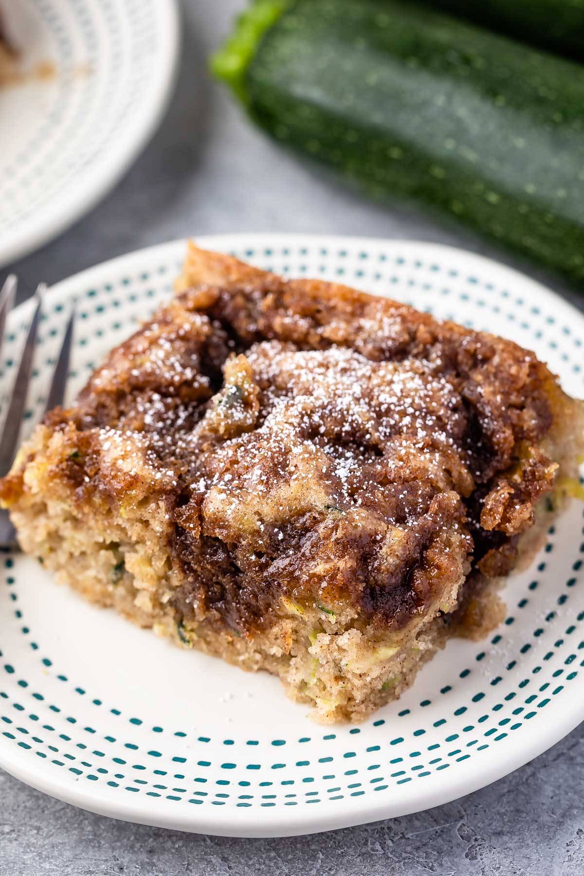square slice of coffee cake on a white plate next to a fork.