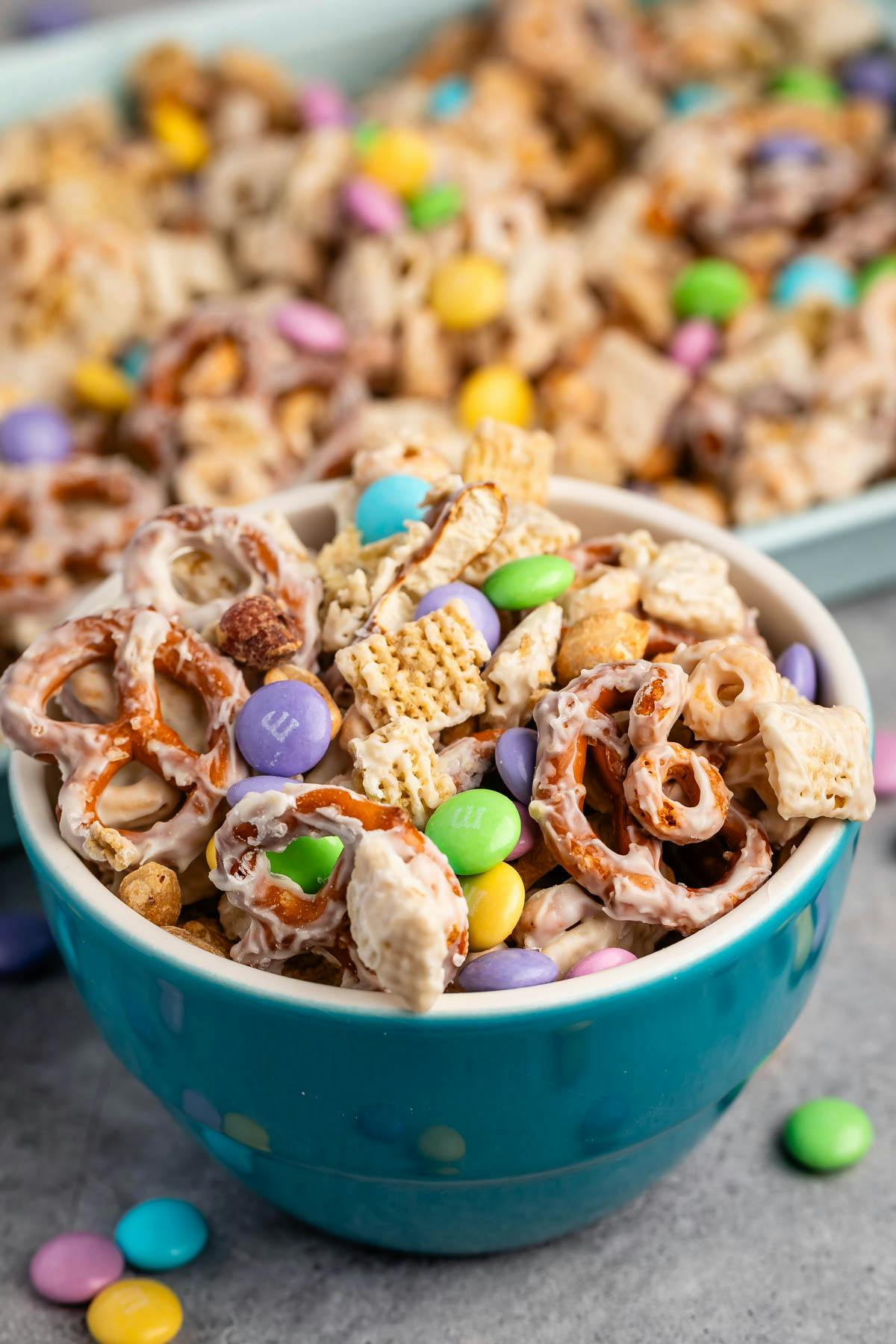 snack mix with pretzels and chocolate candy in a teal bowl.
