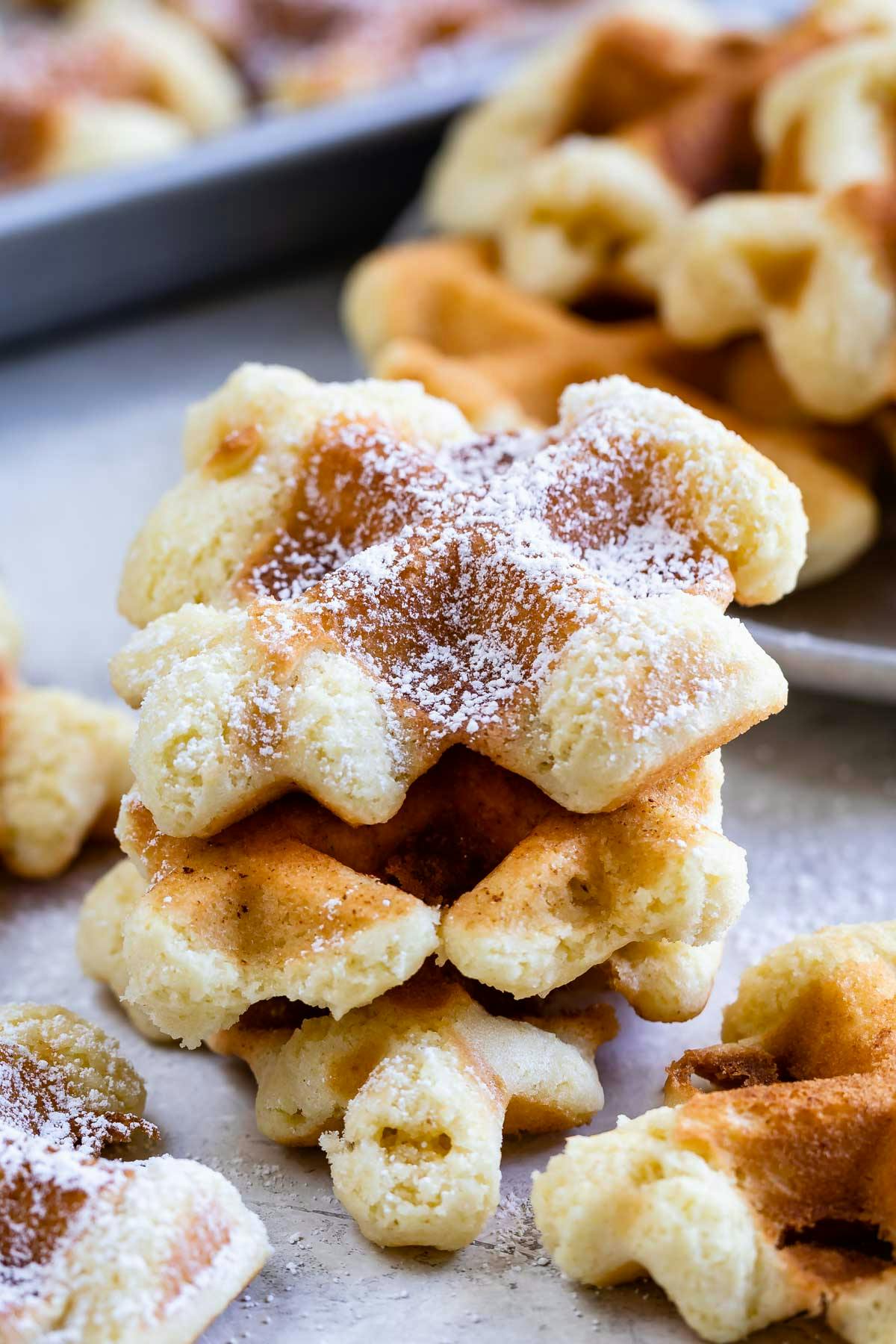 mini waffles stacked and covered in powdered sugar.