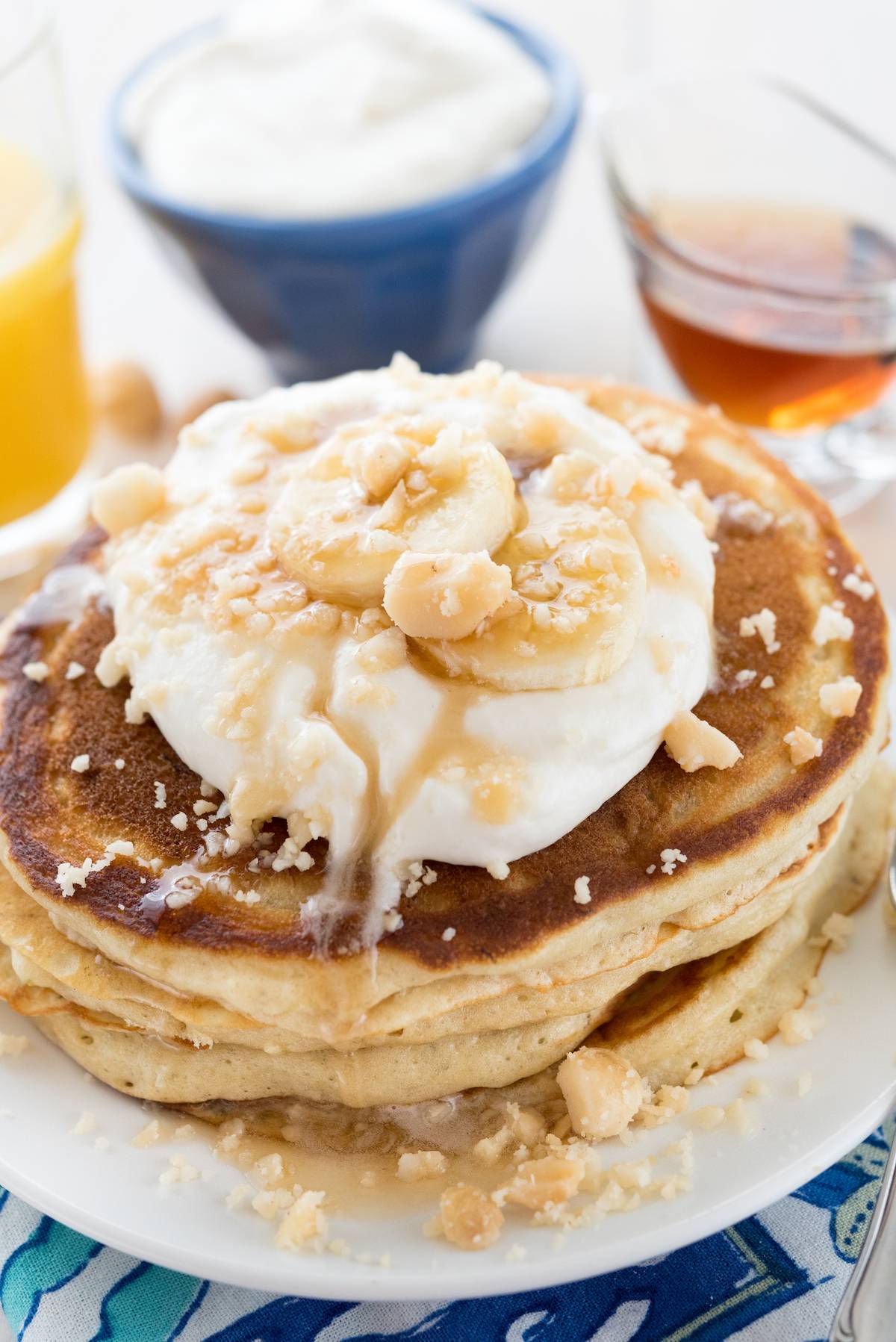 stacked pancakes with whipped cream and sliced bananas on top. 