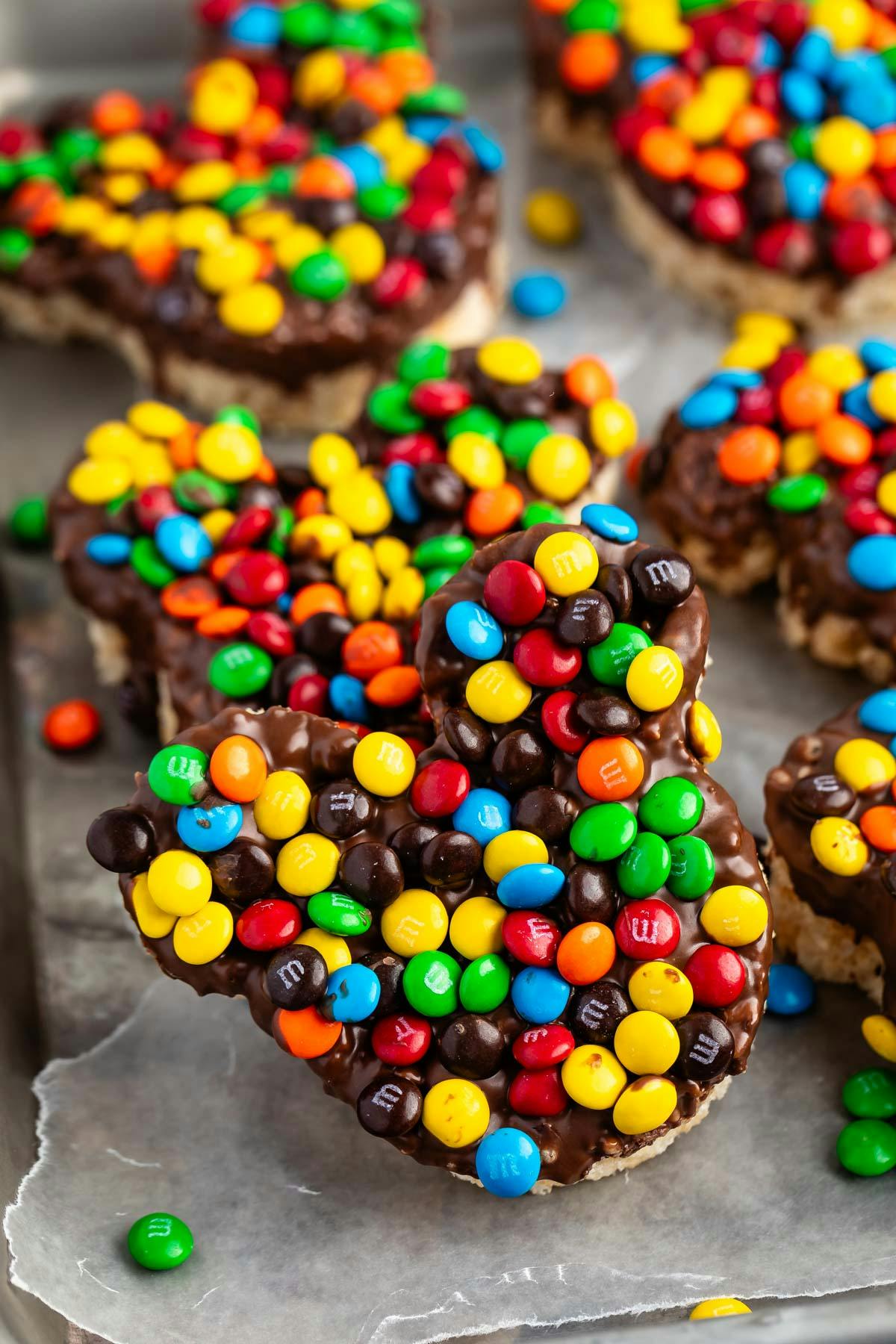 Rice Krispie treats shaped as mickeys with chocolate and colorful candy on top.