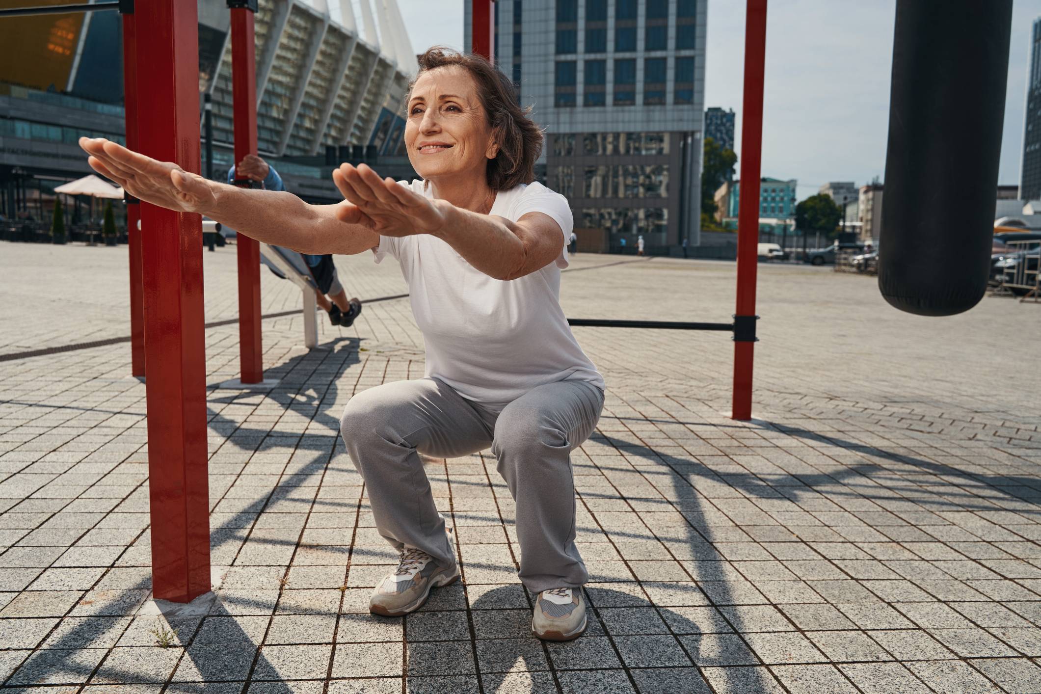 Adult woman doing squats outdoor in exercise park