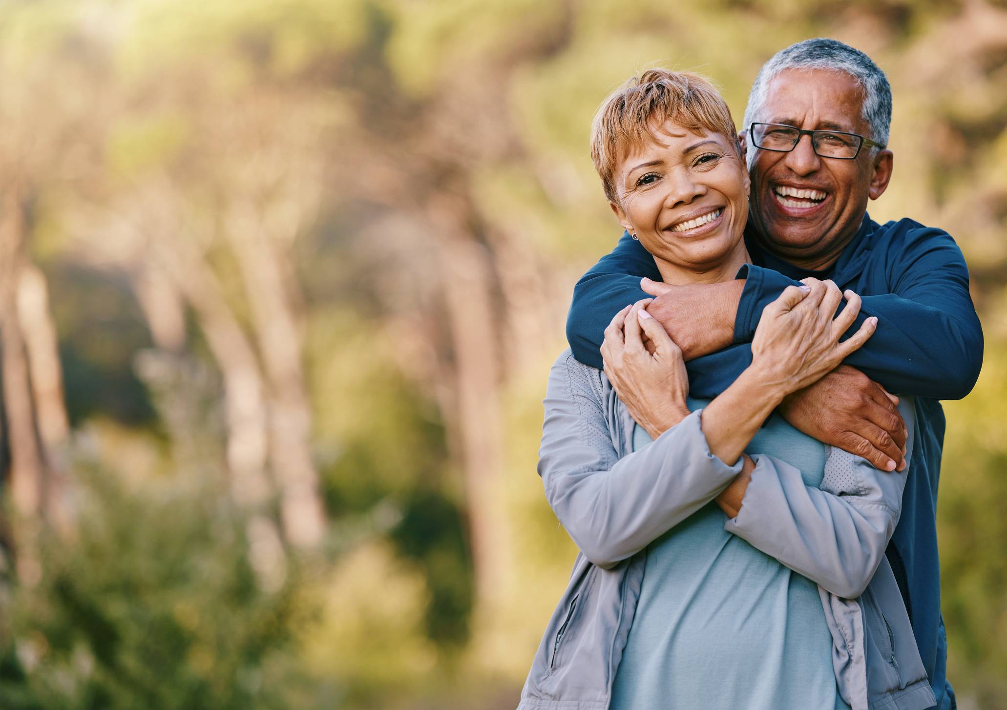 happy older couple hugging in park