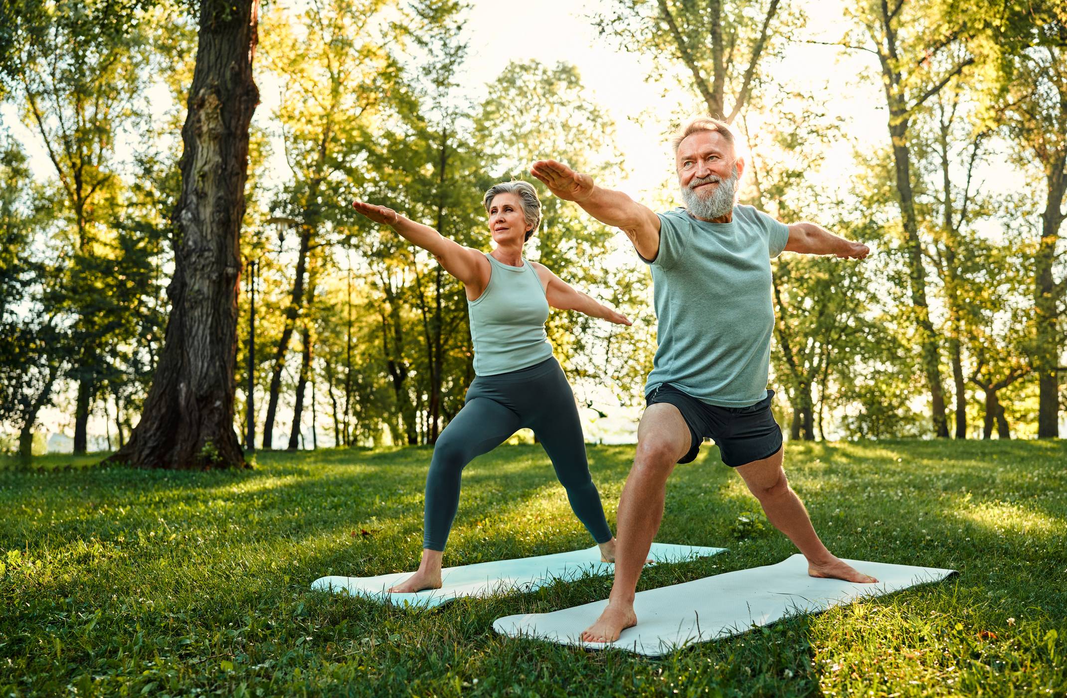 older couple performing yoga outdoors