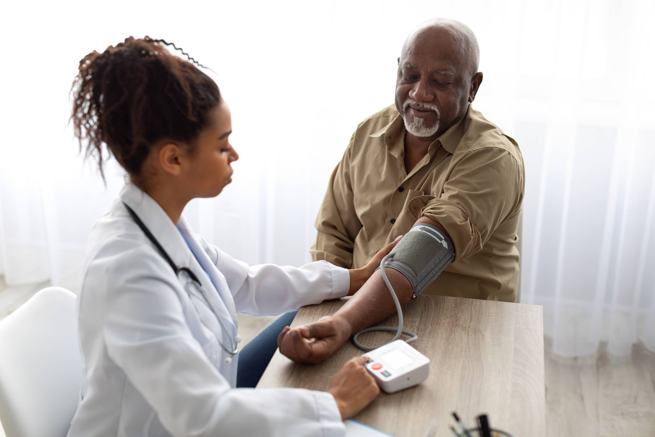female doctor taking blood pressure of senior African American man
