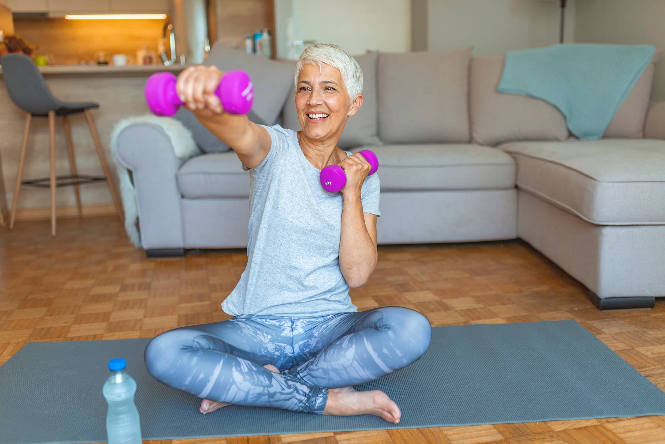 Middle-aged woman exercising in living room with dumbells